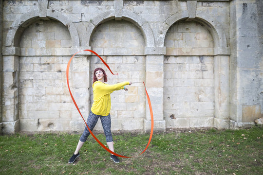 Young woman practising ribbon dance, walled arches in background