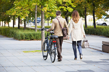 Casual businessman and woman pushing bike