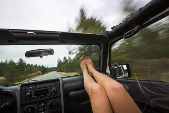 Young woman with feet up whilst traveling in jeep