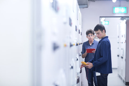 Colleagues in control room testing switchgear with electricity meter