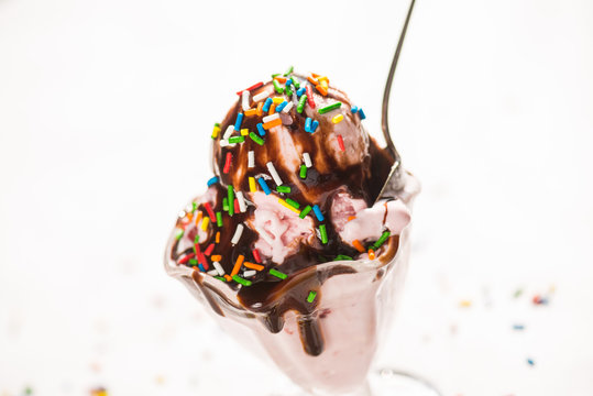 Gooey strawberry ice cream in a glass, covered with chocolate syrup and sprinkles