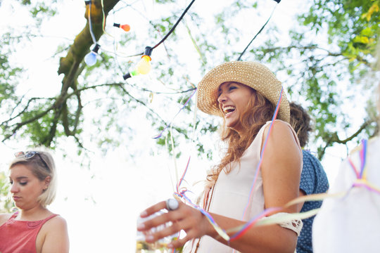 Young adult friends wrapped in streamers at sunset party in park