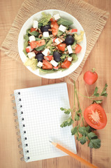 Vintage photo, greek salad with vegetables and notepad for notes, healthy nutrition