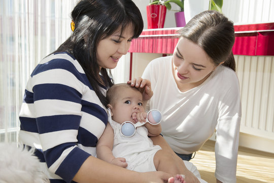 Young woman with mother and baby daughter on floor