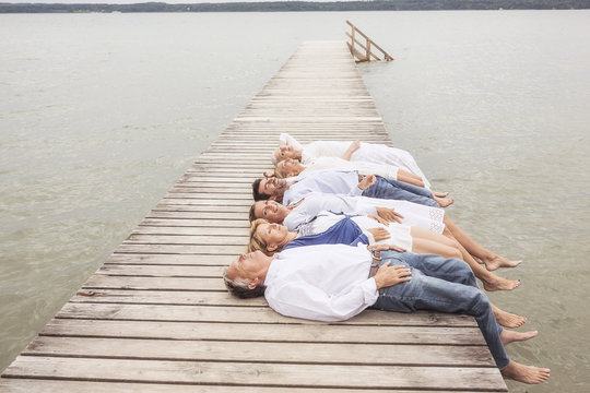 Group of friends lying in a row, on pier