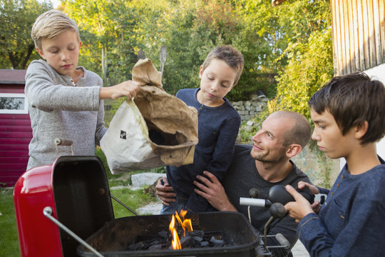 Mid adult man and sons preparing barbecue in garden