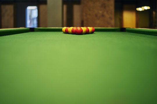 Surface level view of yellow and red pool balls on pool table