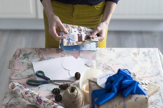 High angle view of mid adult woman wrapping gift at table