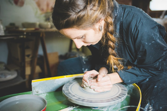 Young woman with plaited hair using pottery wheel - Powered by Adobe