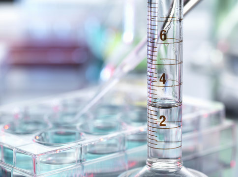 A close up of a volumetric cylinder containing a chemical formula in a laboratory