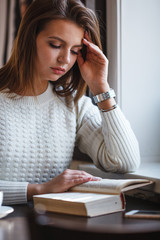 woman reading book at cafe near window