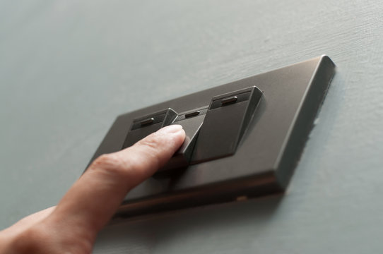 A finger is turning on a light switch