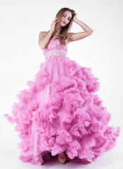 Fototapeta premium Portrait of young beautiful caucasian blonde in gorgeous pink dress on white background