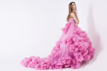 Portrait of young beautiful caucasian blonde in gorgeous pink dress on white background