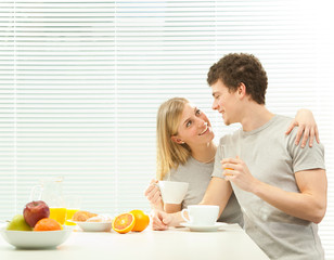 Young casual couple have breakfast with coffee and fruit with venetian blind window