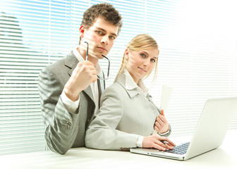 Young business couple work laptop with venetian blind window background