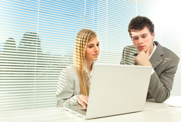 Obraz na płótnie Canvas Young business couple work laptop with venetian blind window background