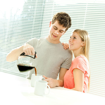 Young casual couple have breakfast with coffee with venetian blind window