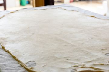Homemade Phyllo or strudel dough on a home table cloth.