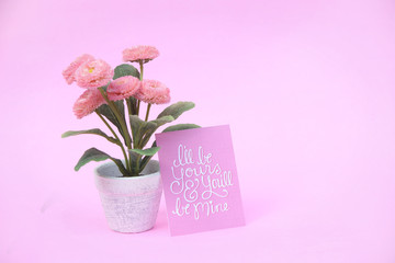 Flower pot with paper note on the pink background