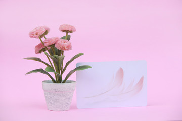 Flower pot with blank paper note on the pink background