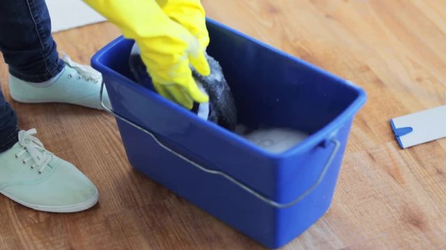 woman washing and squeezing rag in bucket at home