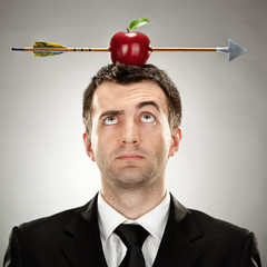 surprised businessman red apple on head hit by arrow on grey background