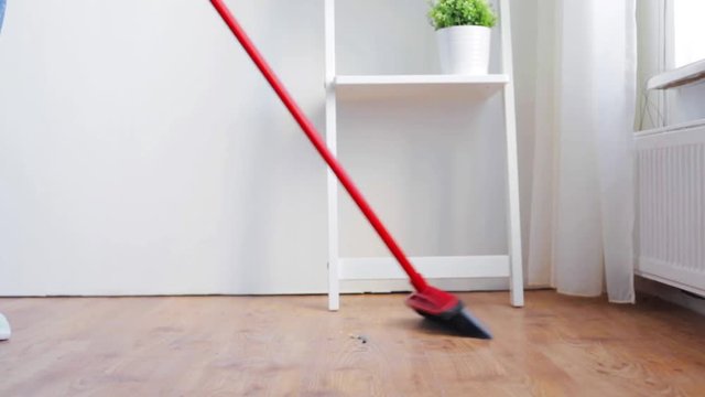 woman with broom cleaning floor at home