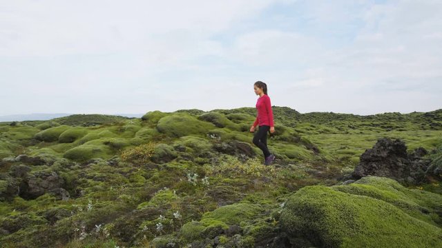 Iceland hiker hiking in moss nature landscape. Woman walking on path trail. Hiker walking in beautiful green mossy lava volcanic landscape. Amazing Icelandic scenery. RED EPIC SLOW MOTION.