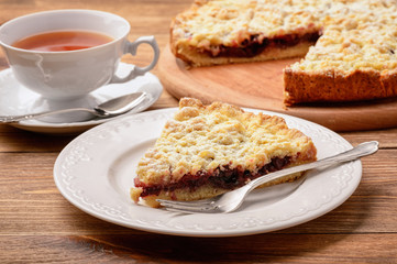 Cherry tart and cup of tea on wooden background.