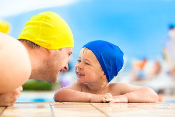 happy child and dad with swimming pool cap have fun in a pool