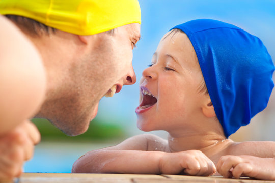 happy child and dad with swimming pool cap have fun in a pool