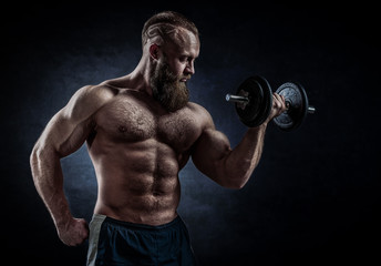Obraz na płótnie Canvas Power athletic bearded man in training pumping up muscles with d