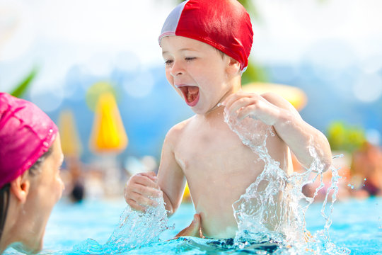 happy child and mom with swimming pool cap have fun in a pool