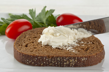 spreading cream cheese on pumpernickel bread