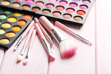 Makeup brush set with palette on a pink wooden table