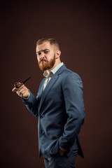 Elegant man with beard holding smoking pipe