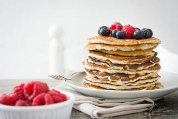 Pancakes with blueberries and raspberries on rustic wood
