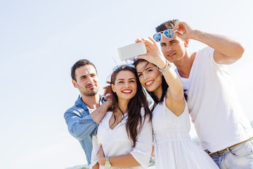 Group of cheerful and beautiful young people taking photos of th