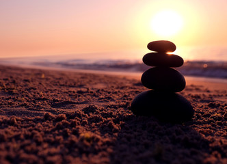 Stones pyramid on the beach at sunset