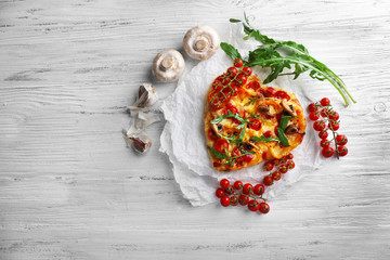 Heart shaped decorated pizza on white cotton serviette on wooden background