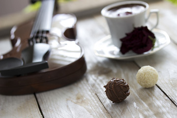 Turkish coffee, truffle chocolate, violin and dried red rose on wooden table