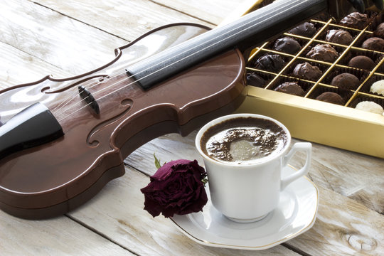 Turkish coffee, truffle chocolate, violin and dried red rose on wooden table