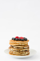 Pancakes with blueberries and raspberries isolated on white background
