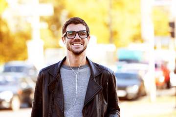 Obraz premium Young man listening to music and walking along the street