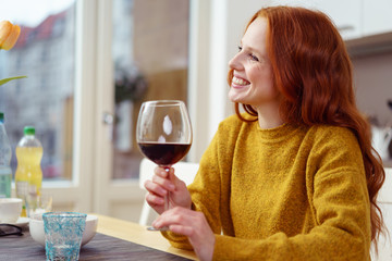 frau sitzt am küchentisch mit einem glas rotwein