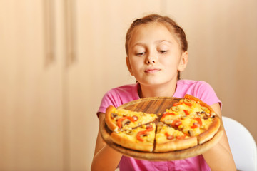 Little girl eating pizza at home