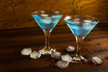 Two glasses of blue cocktail in on dark wooden background