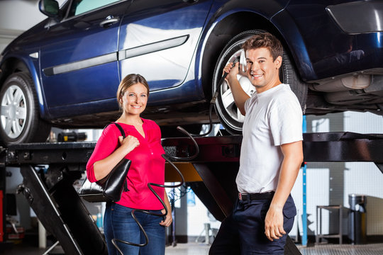 Customer Standing With Mechanic Filling Air In Tire