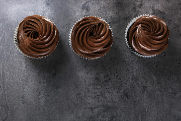 Three chocolate cupcakes on grey background